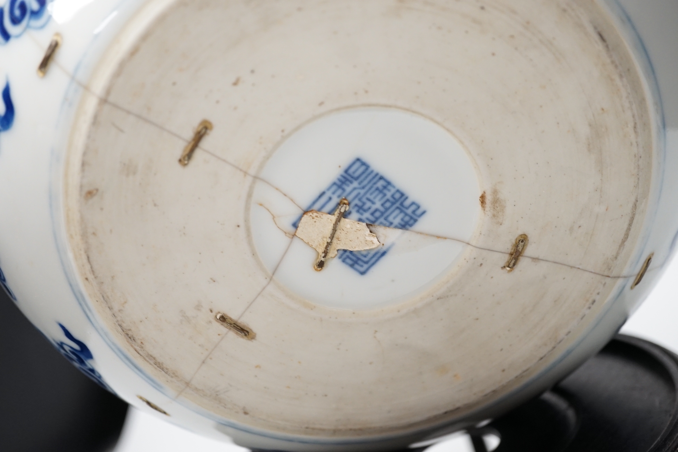 A 19th century Chinese blue and white ‘eight immortals’ alms bowl, apocryphal Qianlong seal mark, 25cm diameter (a.f.), wood stand